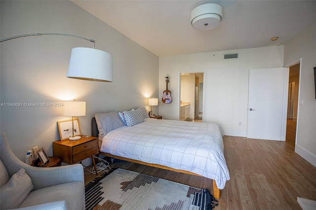 bedroom with ensuite bath and dark hardwood / wood-style flooring