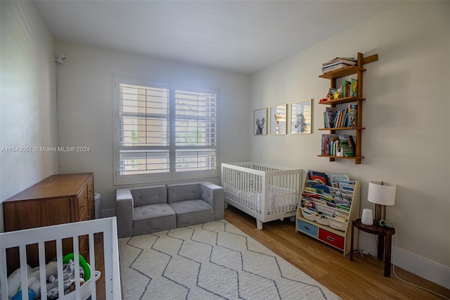 bedroom with a nursery area and light wood-type flooring