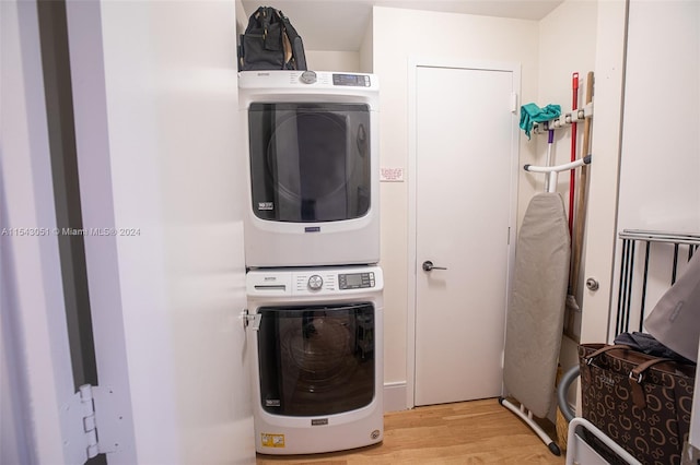 clothes washing area featuring stacked washer and clothes dryer and light wood-type flooring