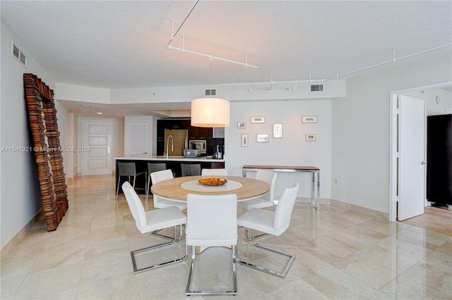 tiled dining space with rail lighting and sink