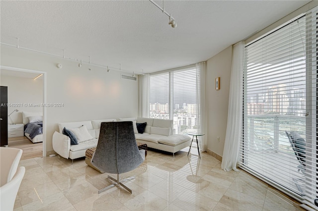 living room featuring light tile floors, a textured ceiling, and rail lighting