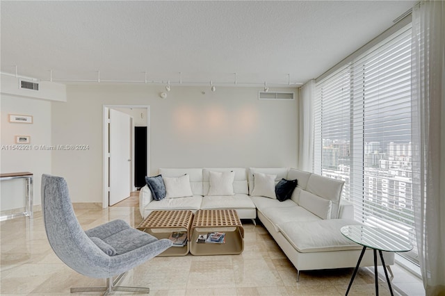 living room featuring a textured ceiling, light tile floors, and rail lighting