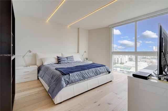 bedroom with light hardwood / wood-style floors and a wall of windows