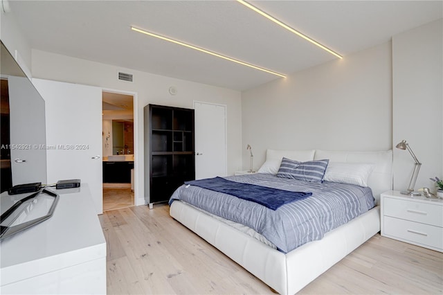 bedroom with light hardwood / wood-style floors and connected bathroom