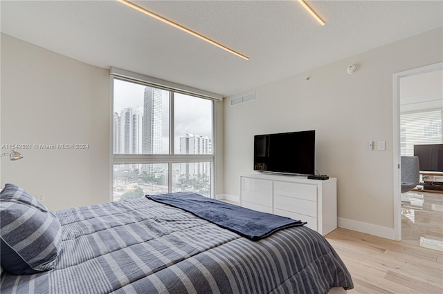 bedroom featuring floor to ceiling windows and light wood-type flooring