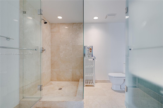 bathroom with toilet, tile floors, and a shower with door