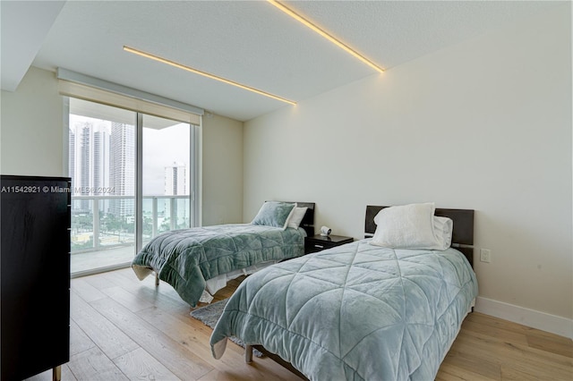 bedroom featuring a wall of windows and light hardwood / wood-style flooring