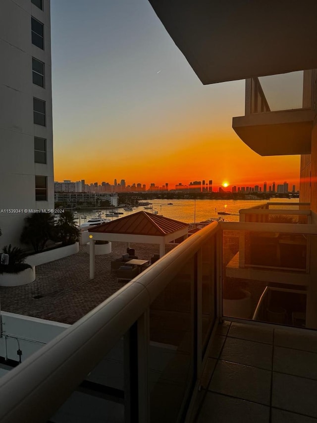 balcony at dusk featuring a water view