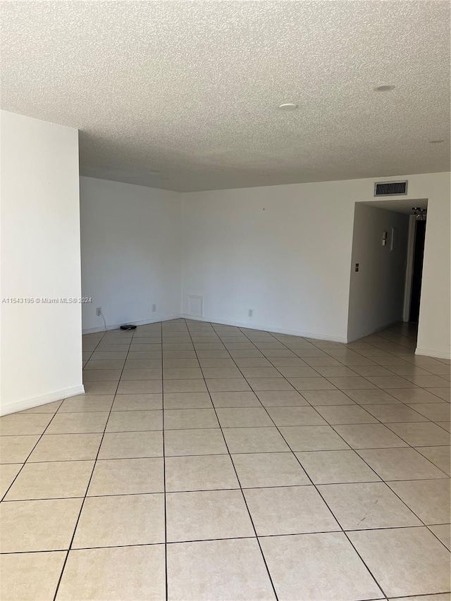 tiled empty room featuring a textured ceiling