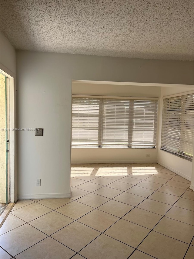 unfurnished room with a textured ceiling and light tile patterned floors