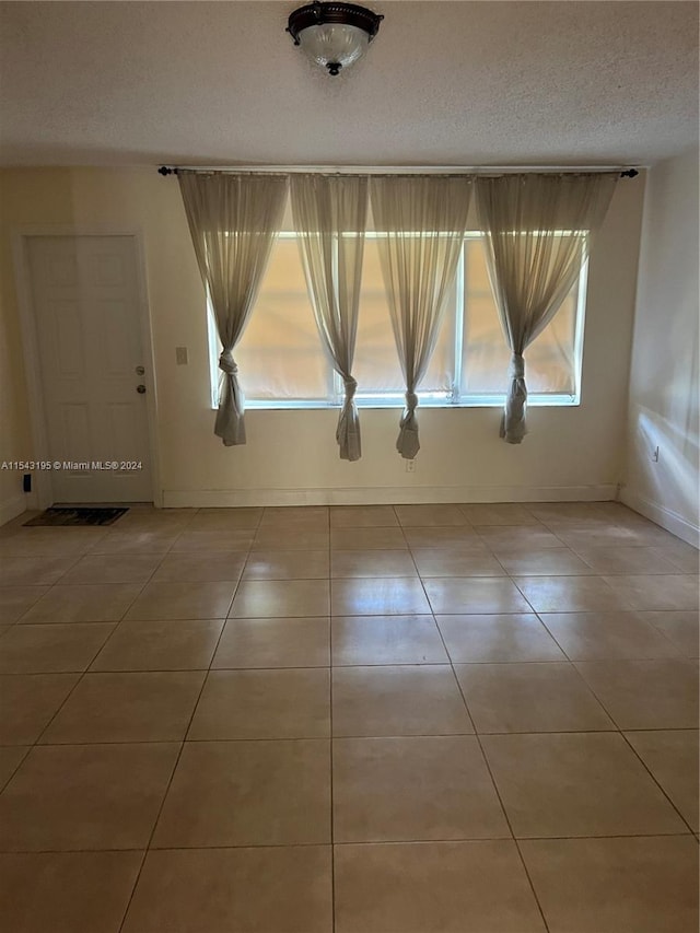 spare room featuring tile patterned flooring and a textured ceiling