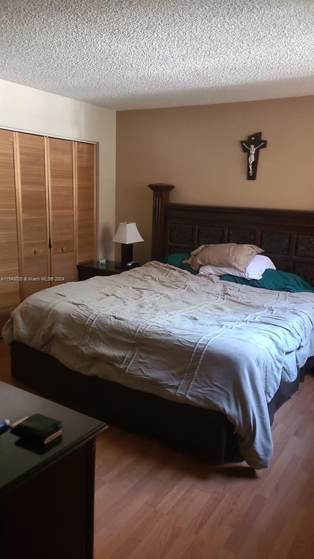 bedroom featuring a closet, a textured ceiling, and dark hardwood / wood-style floors