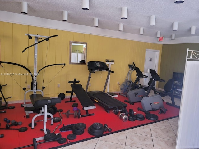 exercise area featuring light tile floors and a textured ceiling