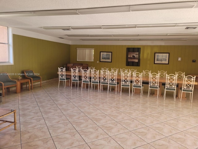 dining area featuring wood walls, light tile floors, and a textured ceiling