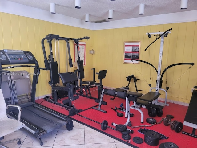 workout area featuring a textured ceiling and light tile flooring