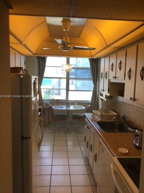 kitchen featuring sink, white cabinets, light tile patterned floors, and white refrigerator