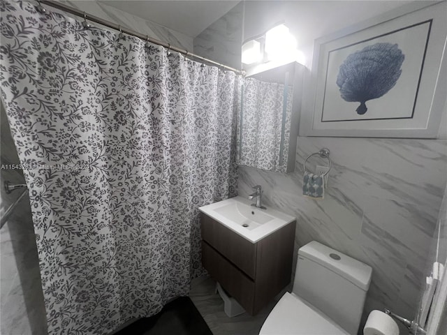 bathroom with oversized vanity, toilet, and tile walls