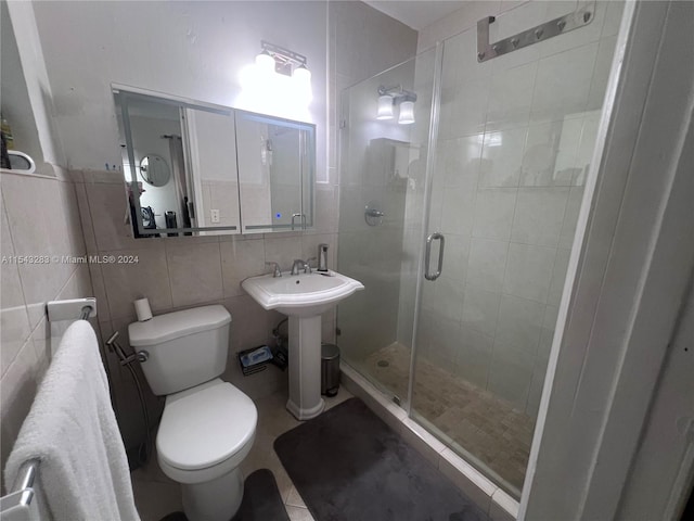 bathroom with toilet, tile walls, tile flooring, an enclosed shower, and sink