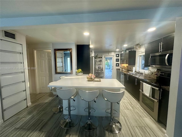 kitchen featuring a sink, modern cabinets, appliances with stainless steel finishes, and dark cabinetry