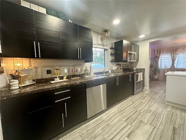 kitchen with open shelves, dark cabinets, stainless steel appliances, and a sink