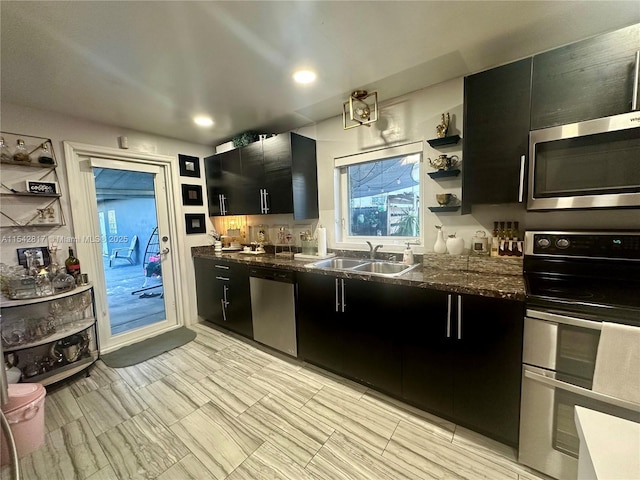 kitchen with stainless steel appliances, open shelves, a sink, and dark cabinets