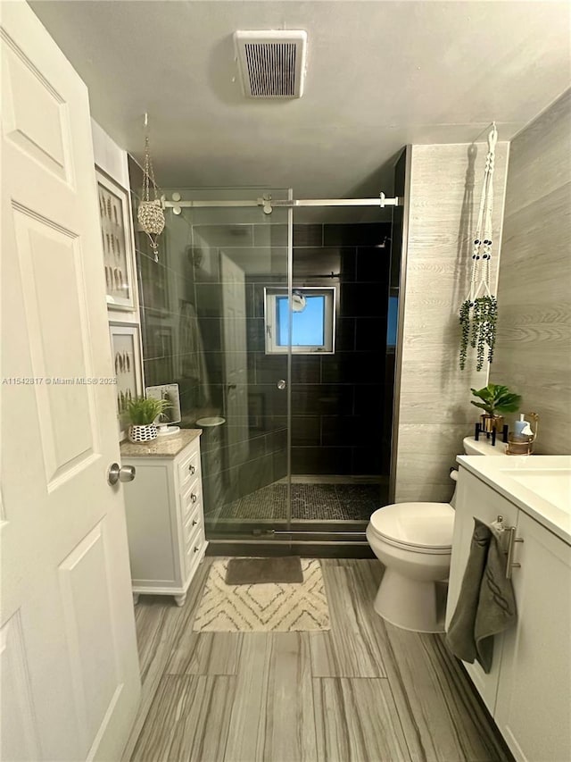 full bathroom with visible vents, toilet, vanity, and a shower stall