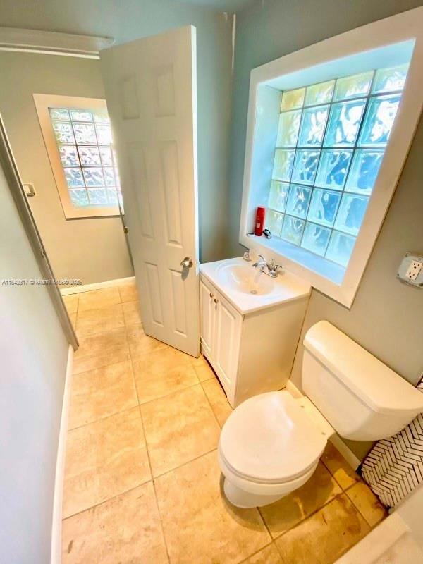 bathroom with toilet, baseboards, vanity, and tile patterned floors