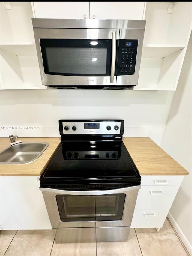 kitchen with open shelves, appliances with stainless steel finishes, a sink, and white cabinets