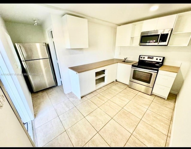 kitchen with stainless steel appliances, butcher block countertops, open shelves, and white cabinets