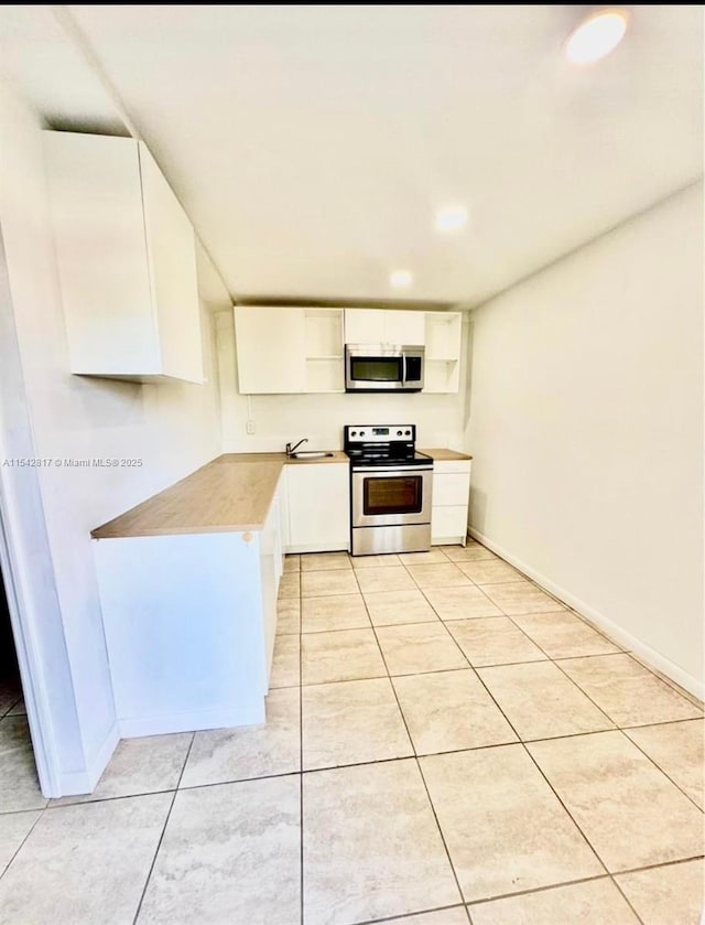 kitchen featuring a sink, white cabinets, light countertops, appliances with stainless steel finishes, and open shelves