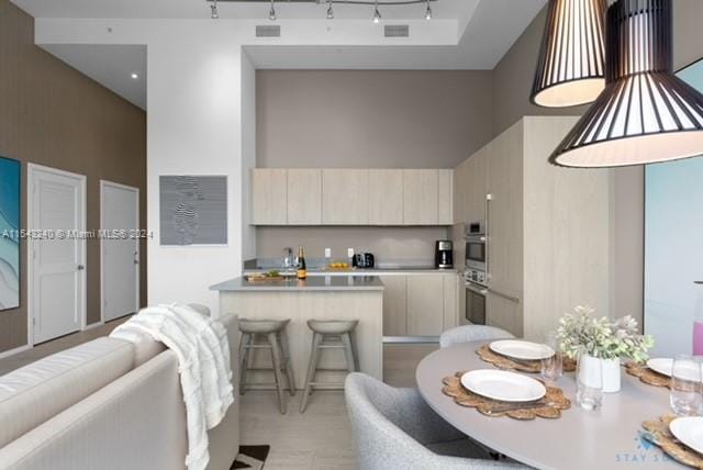 kitchen featuring a high ceiling, a breakfast bar, rail lighting, and cream cabinets