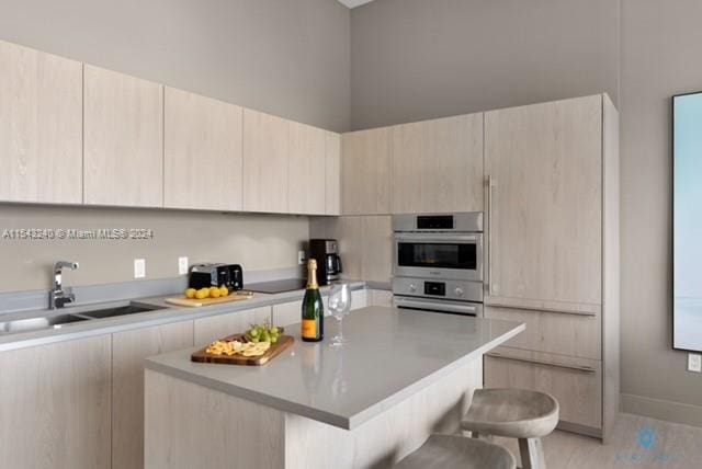 kitchen with double oven, a center island, a breakfast bar, and sink