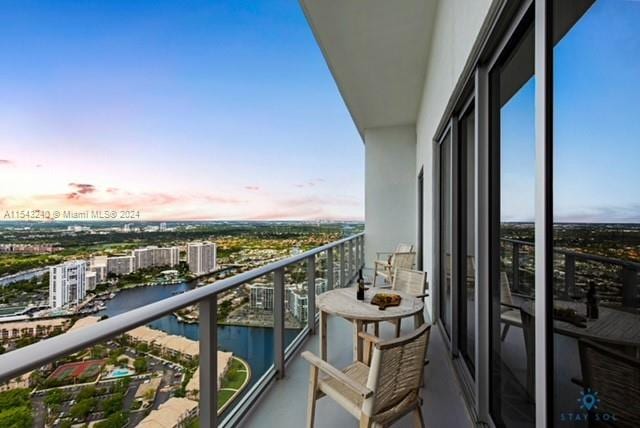 balcony at dusk featuring a water view