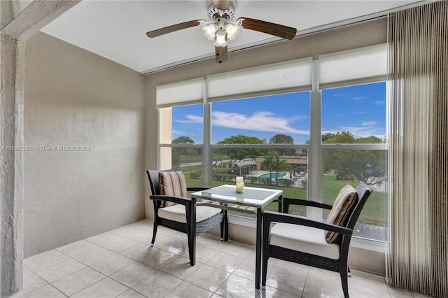 sunroom featuring a water view and ceiling fan