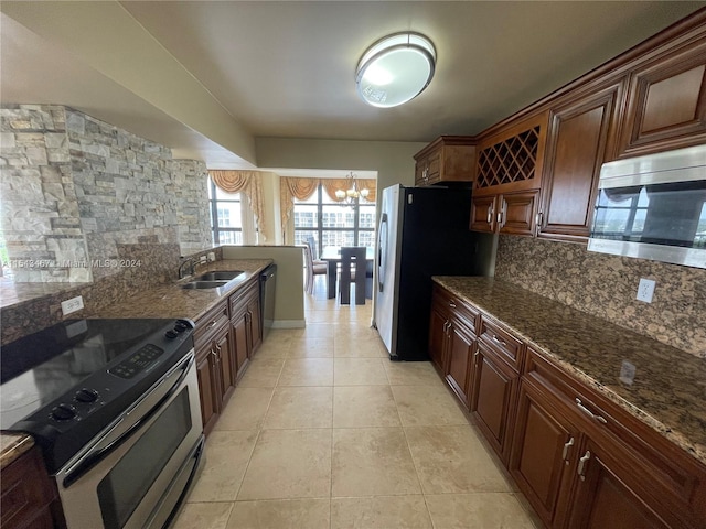 kitchen featuring a notable chandelier, sink, tasteful backsplash, dark stone counters, and stainless steel appliances