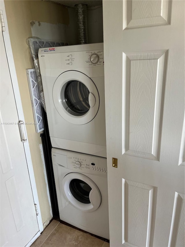 laundry area featuring stacked washer / drying machine and light tile floors