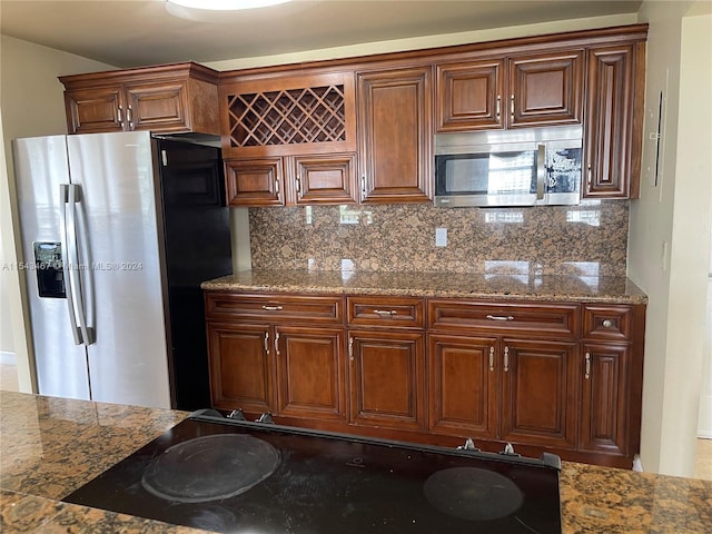 kitchen featuring tasteful backsplash, appliances with stainless steel finishes, and dark stone counters