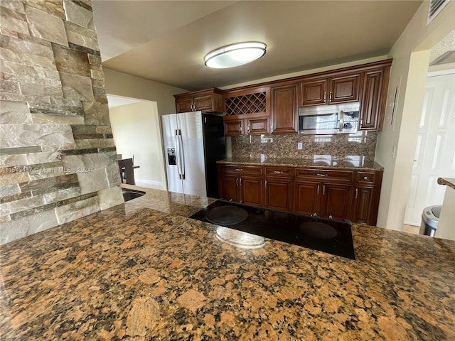 kitchen featuring backsplash, appliances with stainless steel finishes, and dark stone counters