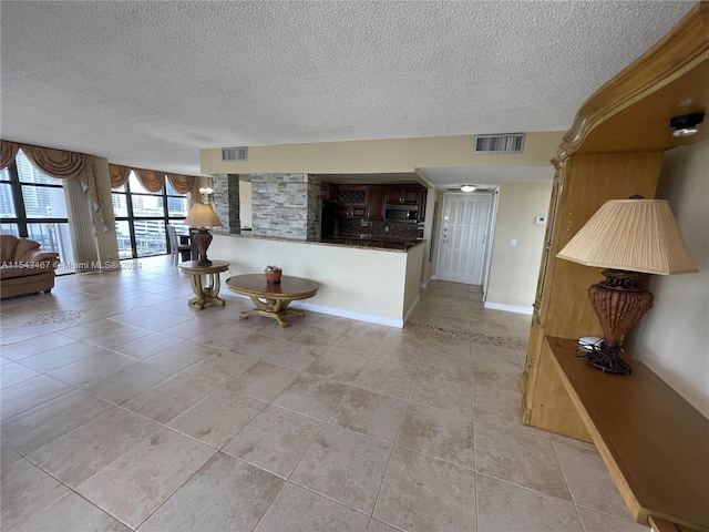 unfurnished living room featuring a textured ceiling and light tile floors