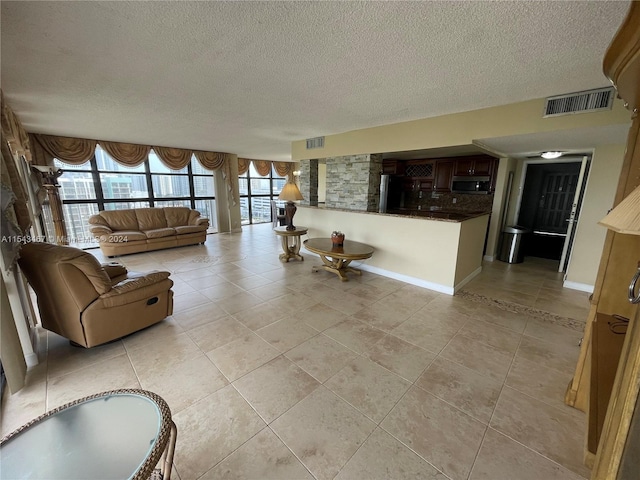 unfurnished living room featuring plenty of natural light, light tile floors, and a textured ceiling