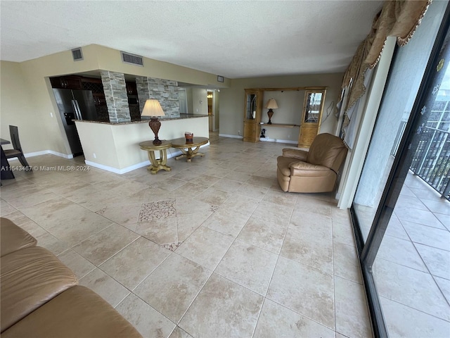 unfurnished living room featuring a textured ceiling and light tile floors