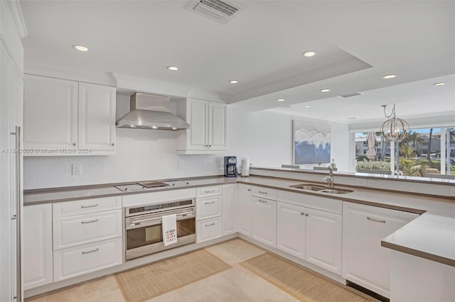 kitchen featuring white cabinets, oven, wall chimney exhaust hood, and sink