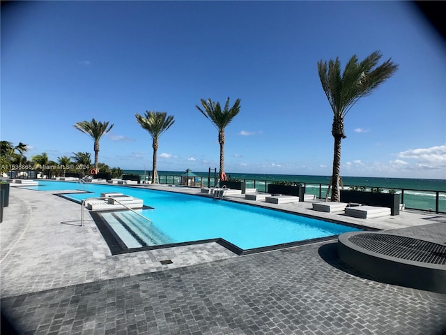 view of pool featuring a patio and a water view