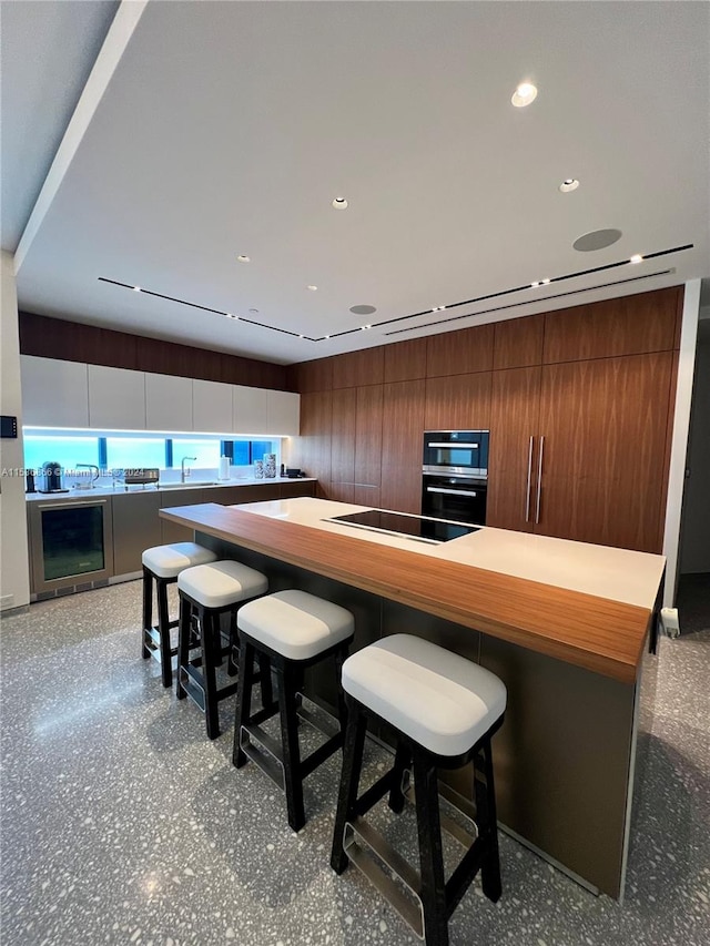 kitchen with a breakfast bar, stainless steel double oven, sink, and electric stovetop