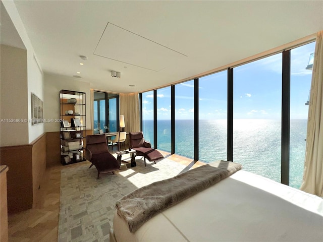 bedroom featuring expansive windows, multiple windows, and a water view