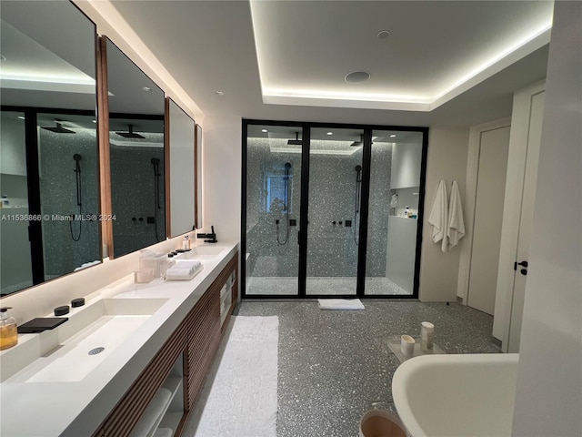 bathroom featuring a raised ceiling, a shower with door, and dual vanity