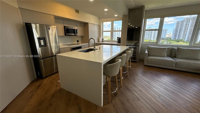 kitchen featuring sink, a kitchen breakfast bar, dark hardwood / wood-style flooring, appliances with stainless steel finishes, and a wealth of natural light