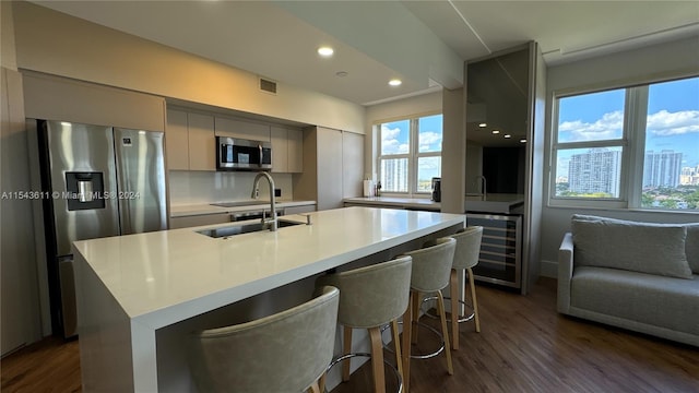 kitchen featuring stainless steel appliances, a kitchen bar, gray cabinetry, dark hardwood / wood-style floors, and sink