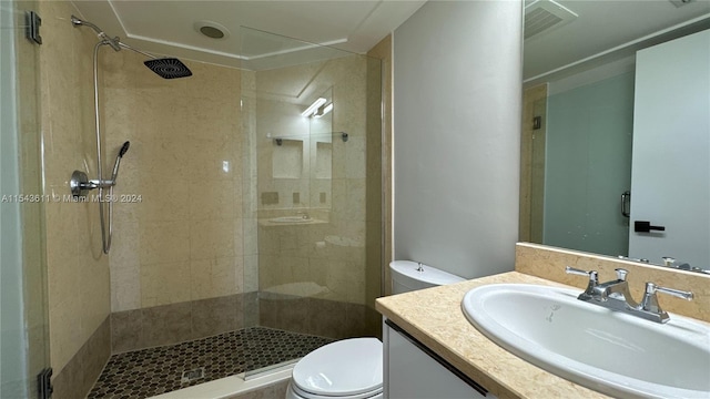 bathroom featuring vanity, a tile shower, and toilet