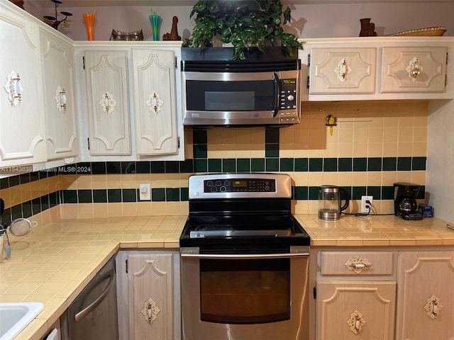 kitchen with light brown cabinetry, tasteful backsplash, stainless steel appliances, and tile counters